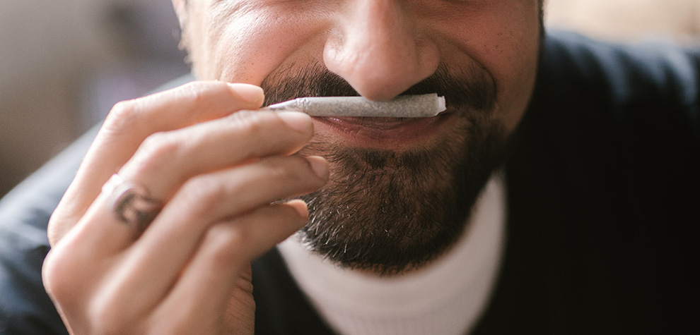 Man sniffing a pre-roll joint of Runtz strain BC cannabis. online dispensary. weed shop. moon rock weed.