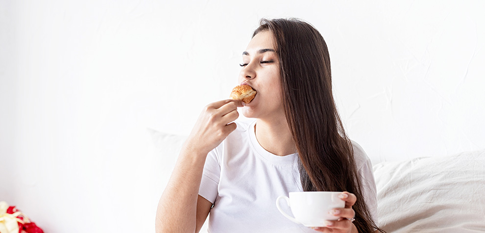 Woman snacking with coffee & pastry. best dispenseries for BC cannabis and hash online. online dispensary. weed shop. 