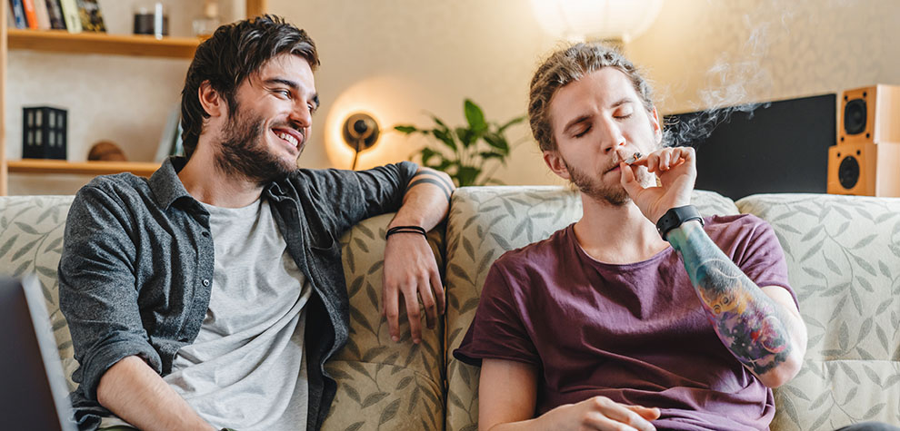 Two guys sharing a joint at home. Ice Cream Cake weed online Canada from online dispensary for BC cannabis MMJ Express. Buy online weeds.