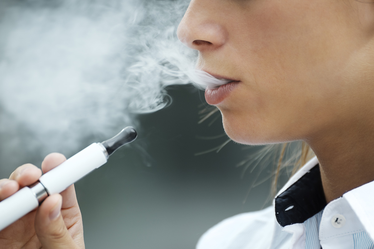 woman using a weed vape pen while exhaling vape smoke.