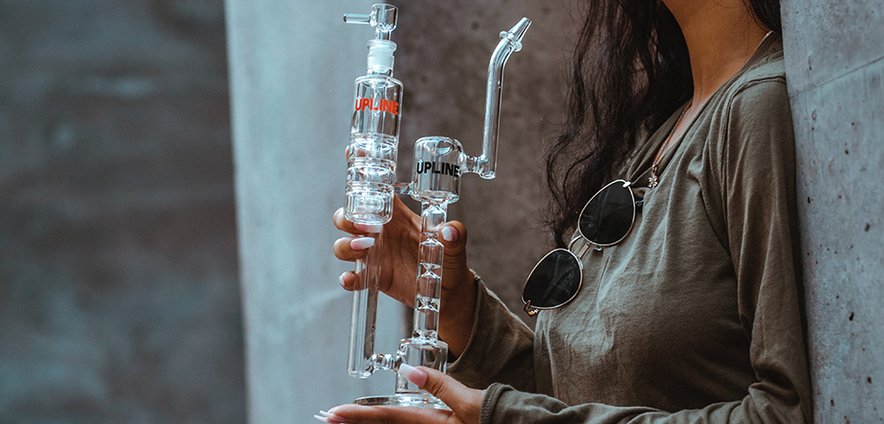 woman using a bong to smoke weed. buy online weeds from cheap weed & value buds weed dispensary MMJ Express. how to smoke weed without papers.