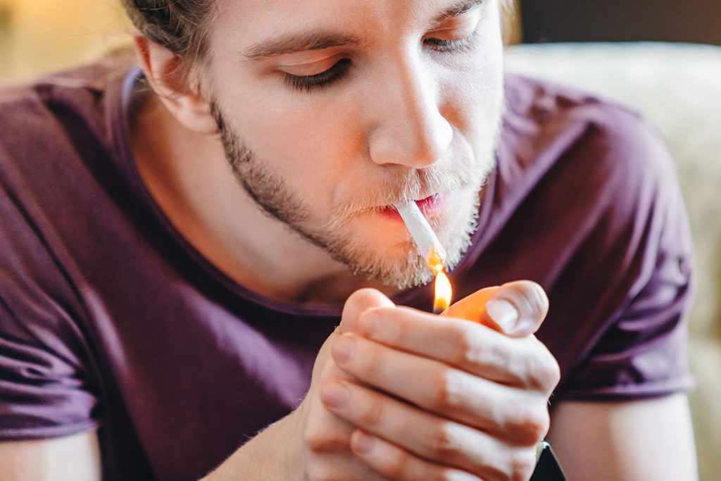 Man lighting a preroll joint of hash. How to smoke hash. Buy weed online Canada.