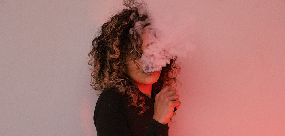 A woman with a weed vape pen ready to vape weed from an online dispensary in Canada for mail order marijuana, shatter, gummys, THC oil, and dispensary weed.