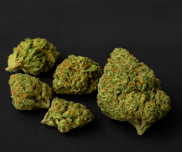 Sour Diesel cannabis buds on a black background, showcasing their dense texture and vibrant green color