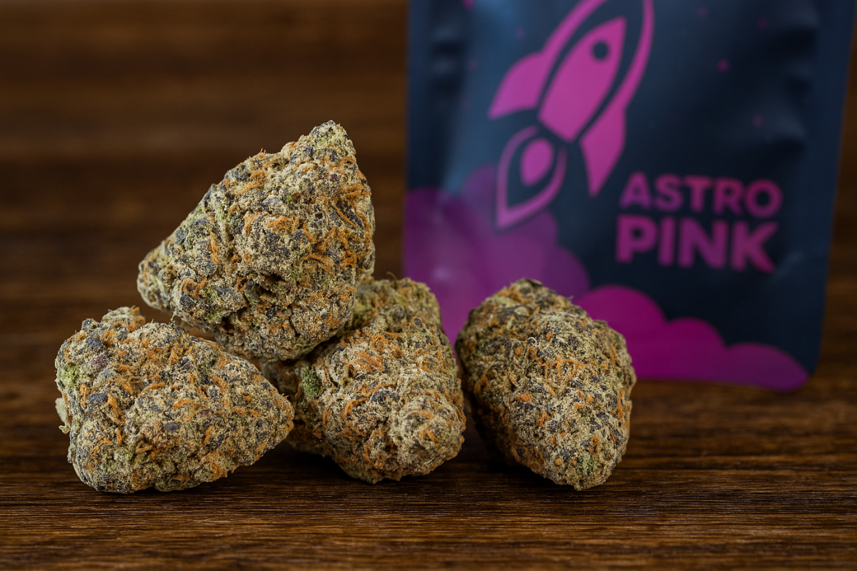 Close-up of frosty Astro Pink cannabis buds in front of branded packaging with a rocket logo on a wooden surface