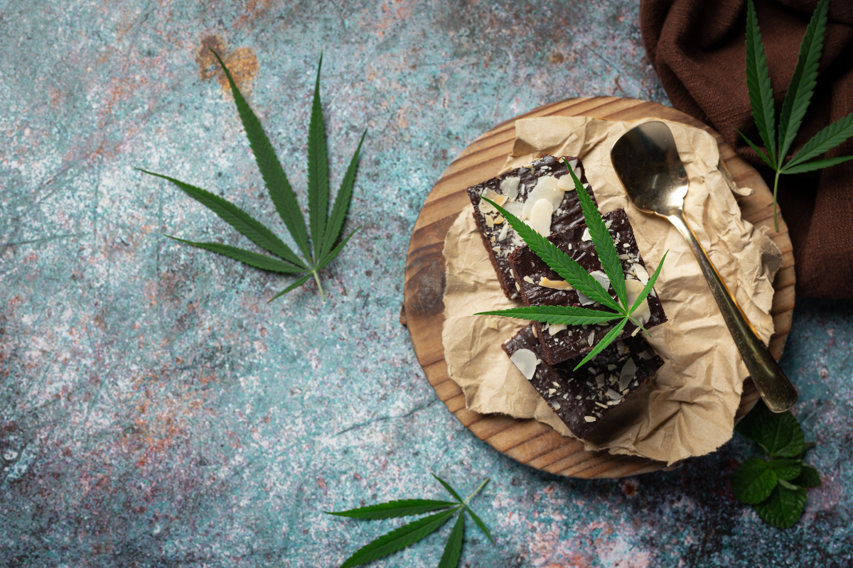 Cannabis brownies garnished with marijuana leaves on a wooden board, representing Wedding Cake strain's premium hybrid appeal