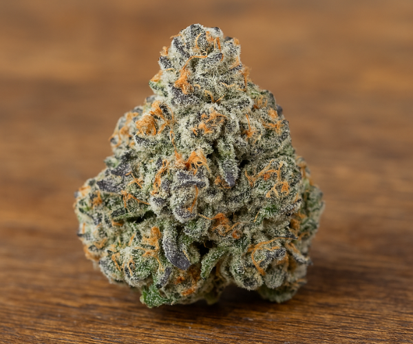 Close-up of Slurricane strain bud showing frosty trichomes and purple-orange hues on a wooden surface