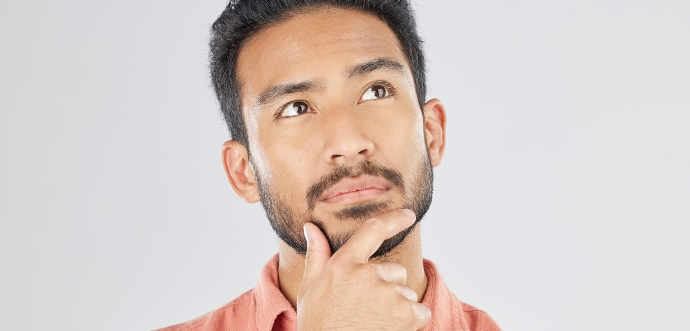 Man in pink shirt looking up thoughtfully, considering why to buy weed online in Canada