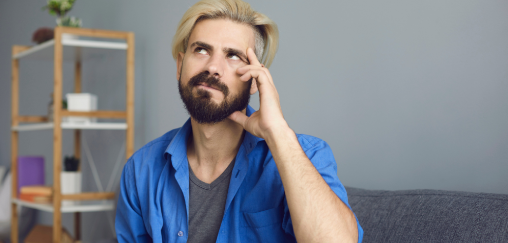 Thoughtful man sitting on a couch with hand on chin, symbolizing decision-making for key factors when buying edible gummies