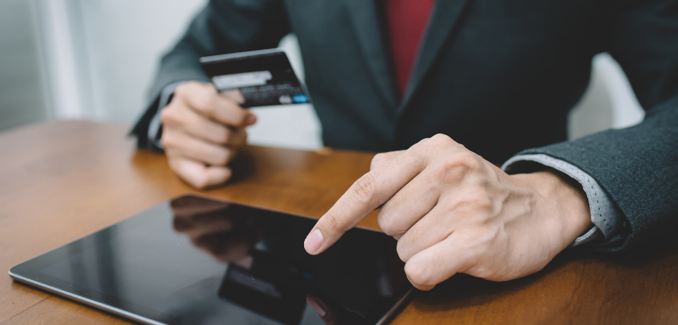 Person in suit holding a credit card and using a tablet, symbolizing the ease of buying the Tropicana Cookies strain online