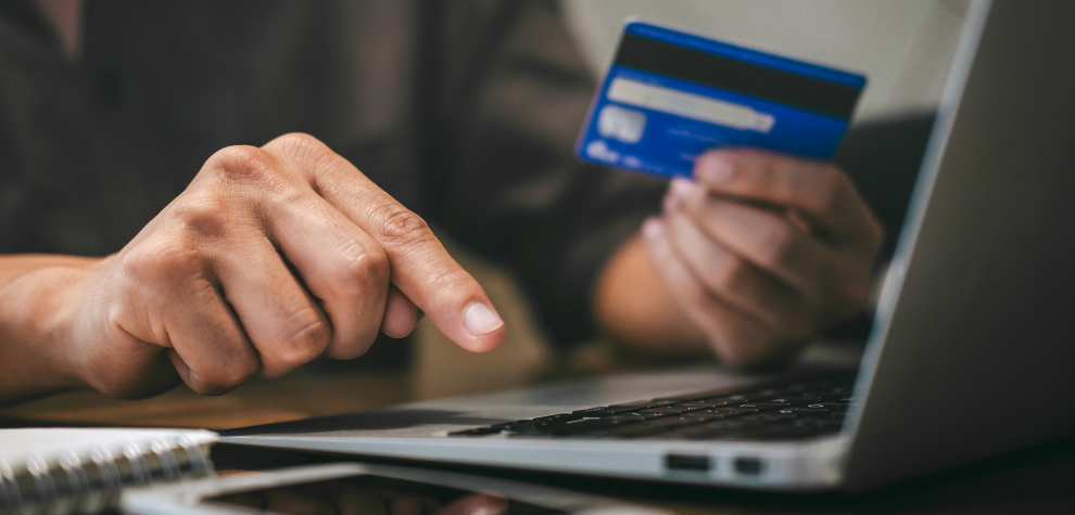 Person holding a credit card and using a laptop, symbolizing the convenience of buying pink weed strains online in Canada