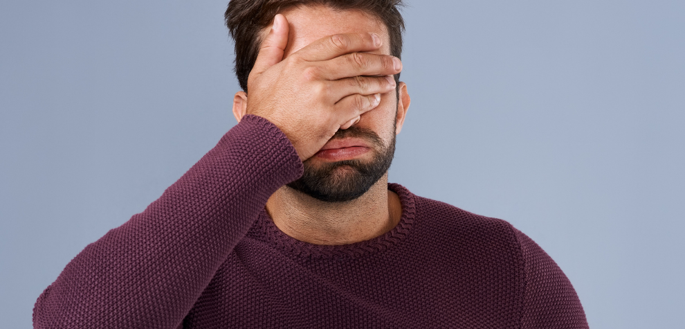 Frustrated man covering his face with his hand, symbolizing common mistakes made when preparing weed butter and how to avoid them