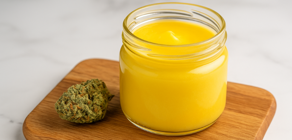 Jar of golden hash butter beside cannabis bud—shows potency of finished infused product for edibles